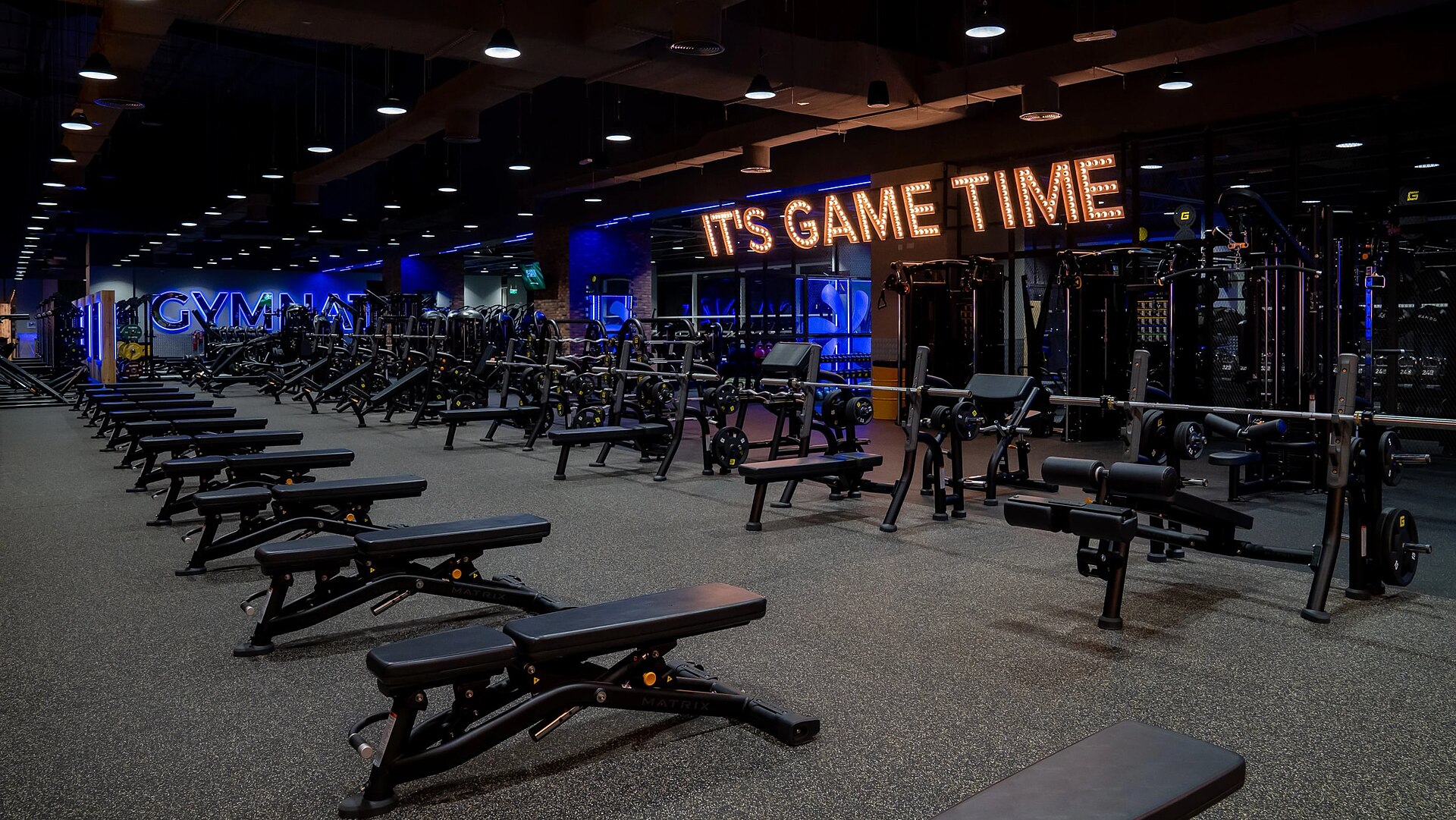 Modern gym interior with weight stations and training equipment.